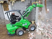 mininakladač avant s hydraulickým kladivom pri búraní steny domu
